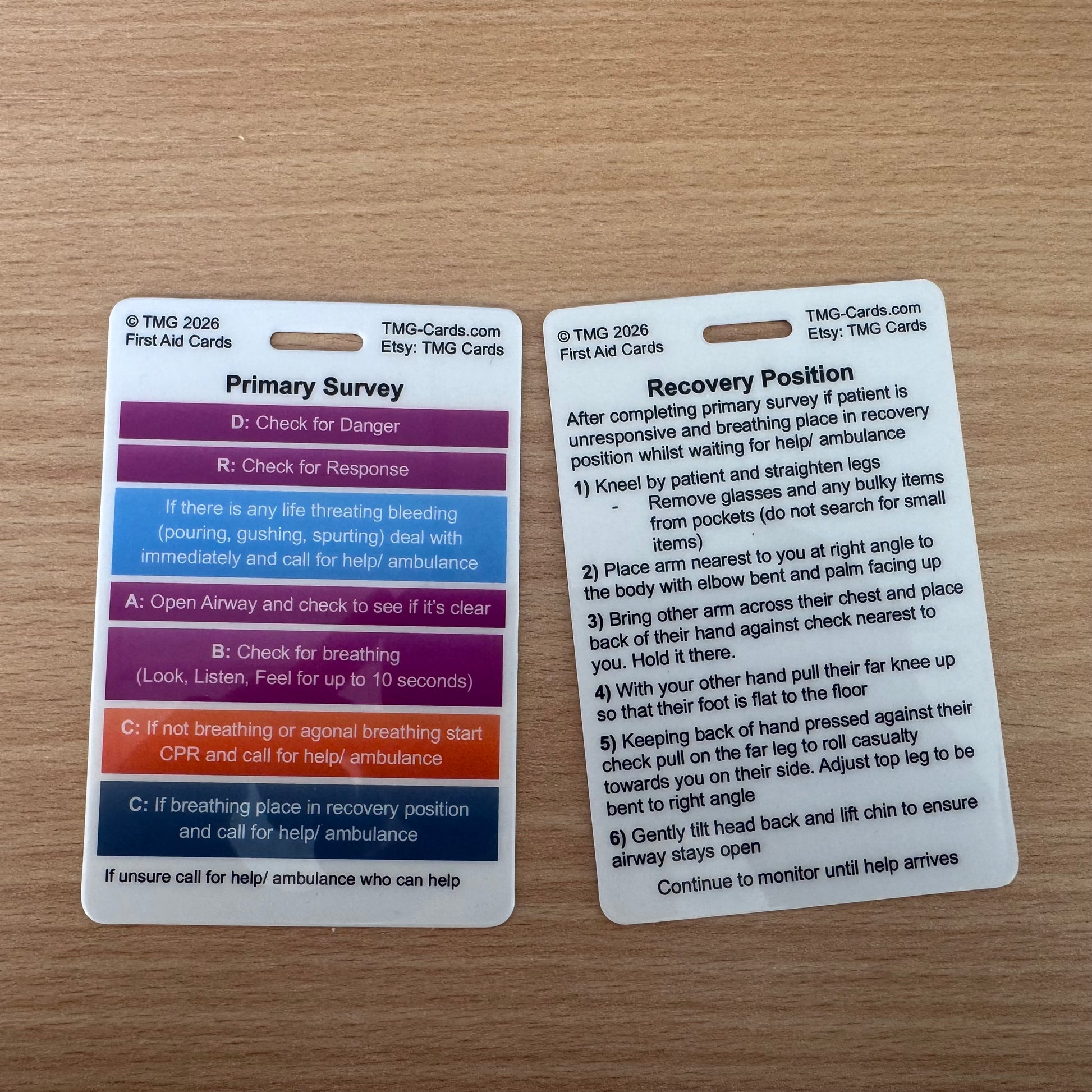 1 Double sided First Aid Emergency reference card showing information for Primary Survey on front and Recovery Position on rear. TMG Cards
