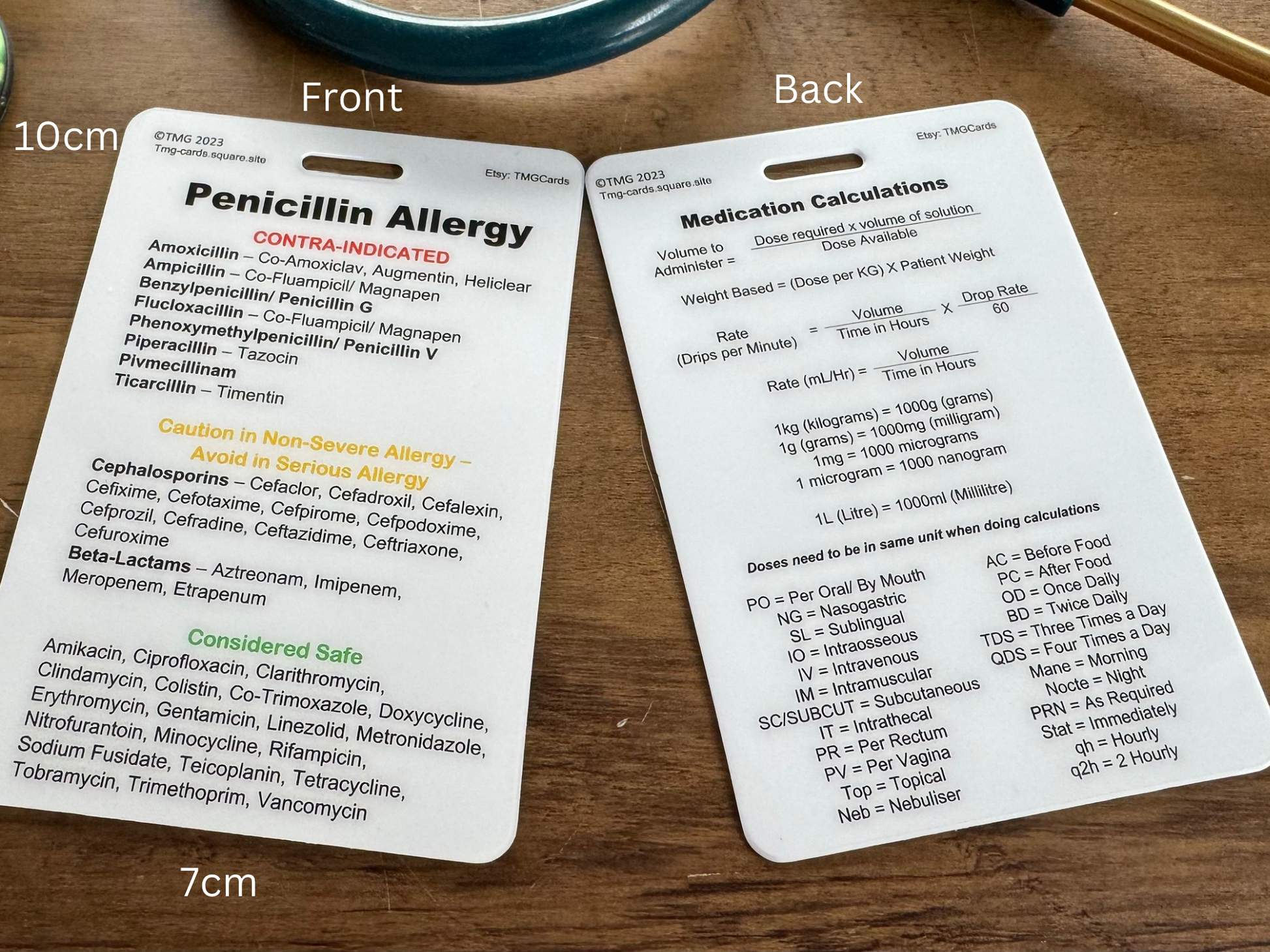 Front and rear of the Medication Calculations and Penicillin Allergy card laid on a wooden surface White measurement text overlays indicate 10cm and 7cm.
The front has Penicillin Allergy information and the rear has Medication Calculations Formulas and key abbreviations. TMG Cards